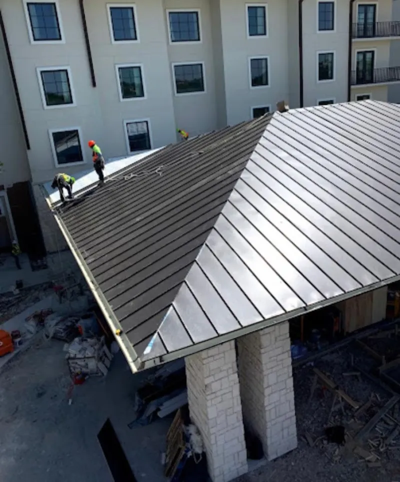Crew installing standing seam metal roof panels on a commercial project in Tomah